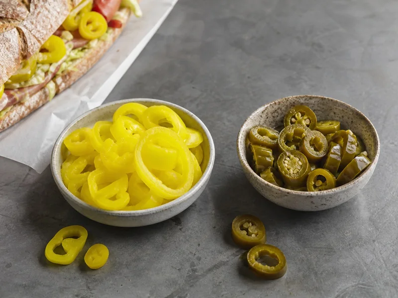 Pickled banana pepper rings and jalapeño rings served in separate bowls