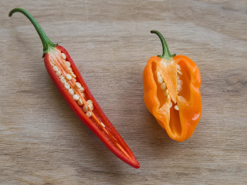 Cut fresh cayenne and habanero peppers showing their flesh and inner membranes