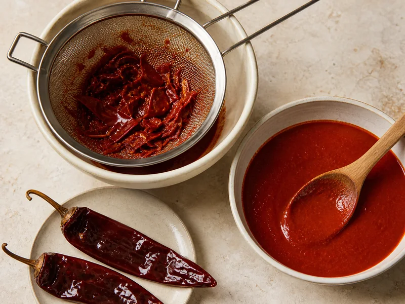 Guajillo skin pressed through a sieve beside smooth strained red chile sauce