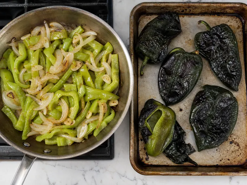 Cubanelle strips frying with onions beside blistered poblano peppers ready to peel