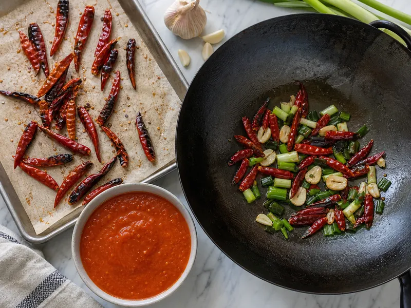Toasted De Arbol chiles and red salsa beside Tien Tsin chiles frying with garlic and scallions