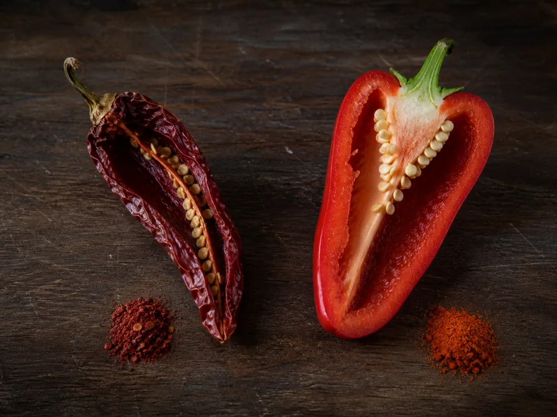 Whole dried Kashmiri chilies beside sweet paprika pepper and ground paprika