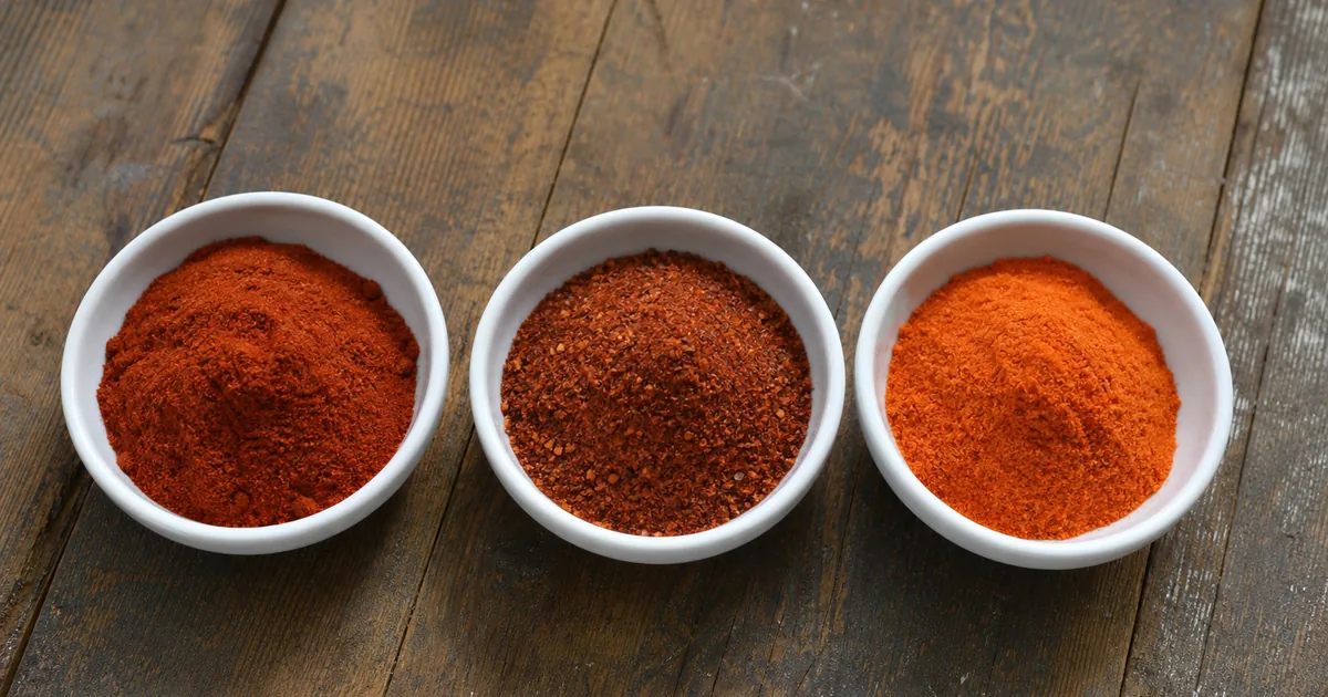 Paprika, chili powder, and cayenne pepper in bowls showing color and texture differences