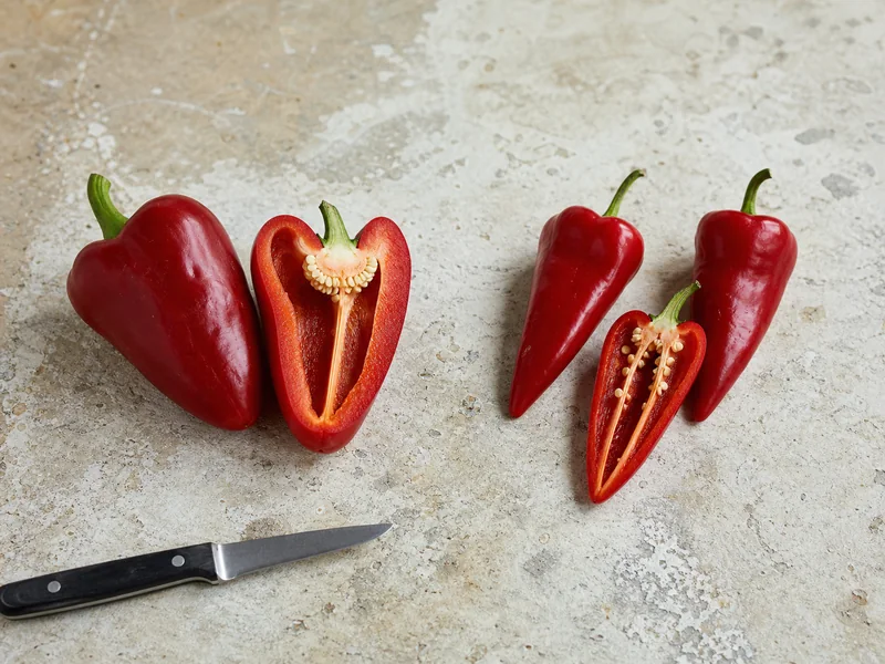 Fresh pimento and piquillo peppers cut open to compare their walls and shape