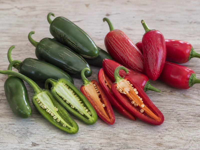 Green and red jalapenos side by side showing the colour and wall difference at each ripeness stage