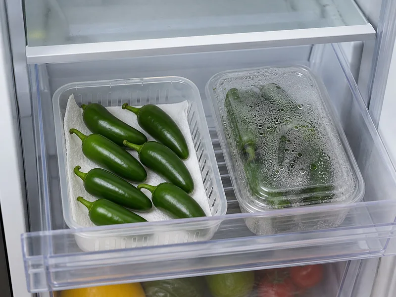Dry jalapenos in a vented container beside a wet condensed clamshell