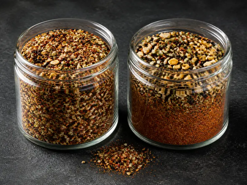 Two clear jars showing evenly shaken shichimi beside a settled blend with fine chile below larger seeds and peel