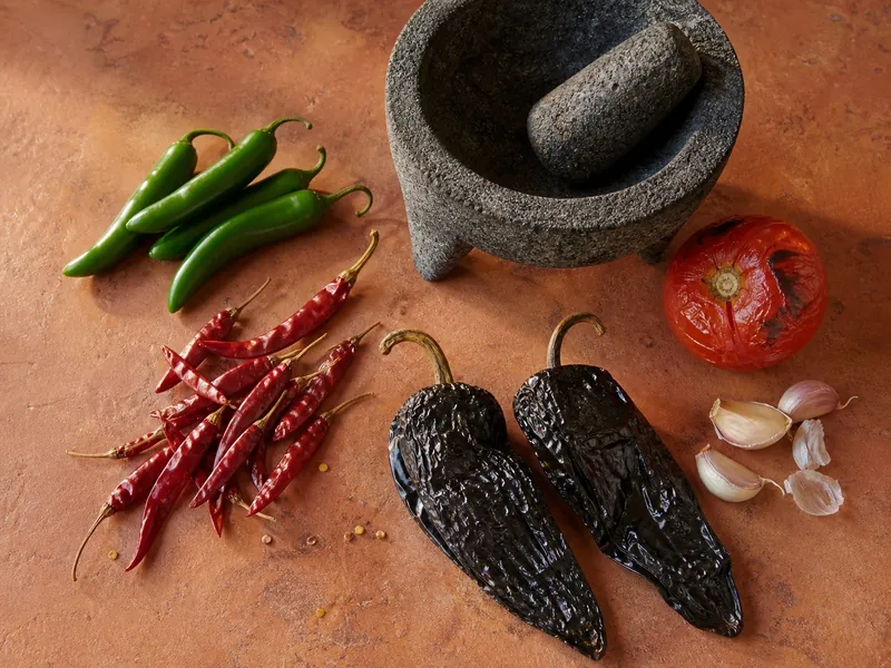 Fresh serranos, dried chile de arbol and Pasilla de Oaxaca beside a molcajete