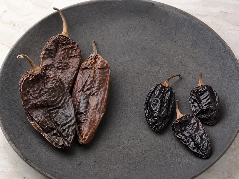 Large tan chipotle meco pods beside smaller dark mahogany morita pods